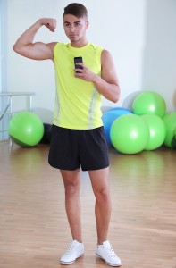 Guy photographing yourself in mirror at phone in fitness room